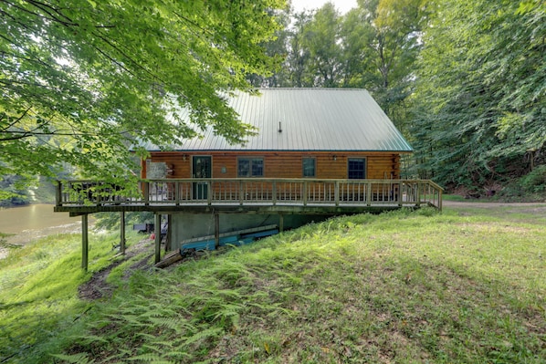 A cabin with a deck, surrounded by dense forest and a river. - Dock & River Access: Custom-built Cabin in Oneonta (Maryland)