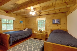 A cabin with two wooden beds, a ceiling fan, and a window with a view of trees. - Dock & River Access: Custom-built Cabin in Oneonta (Maryland)