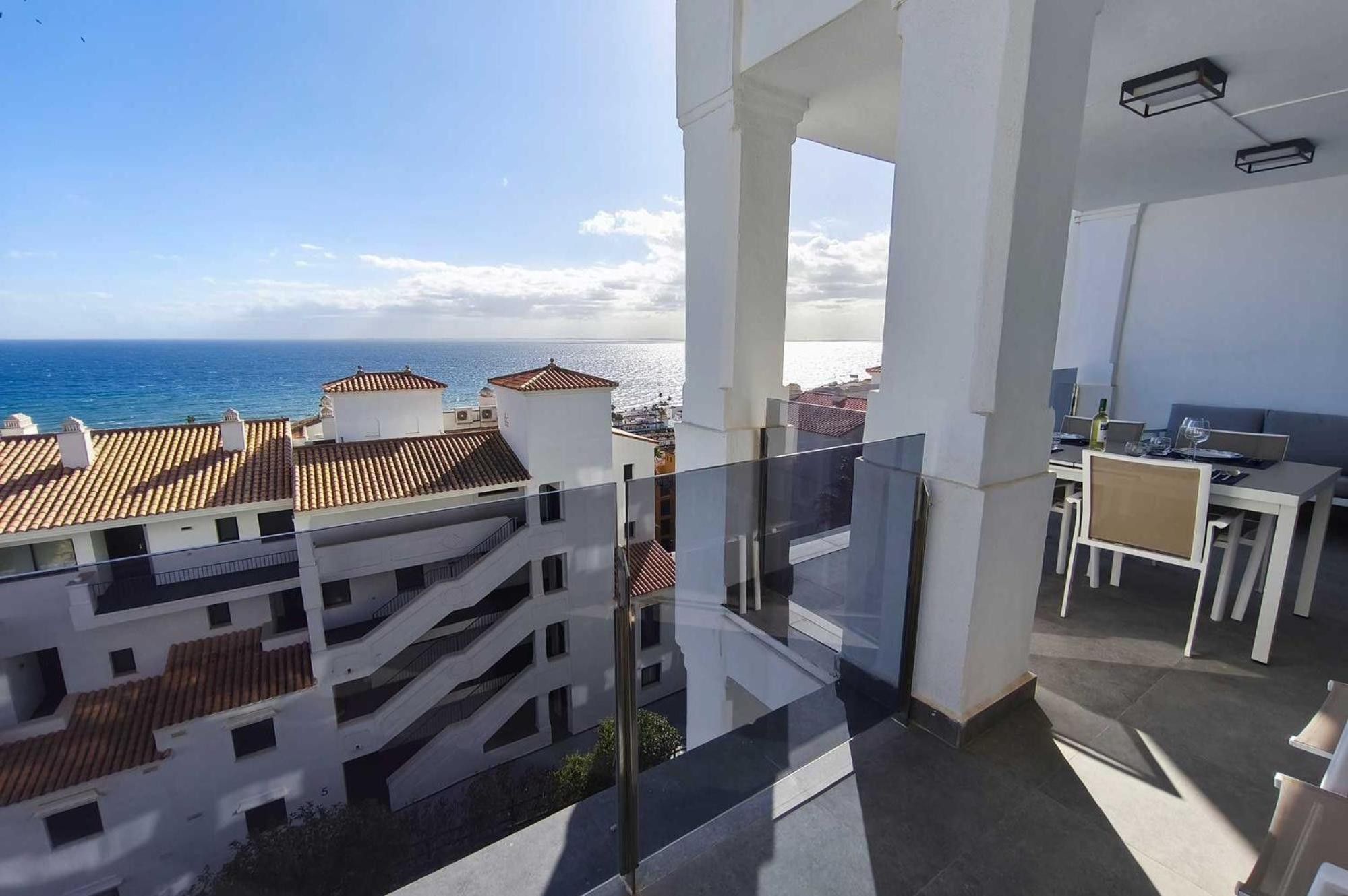 Un balcón con vista al mar y edificios cercanos.