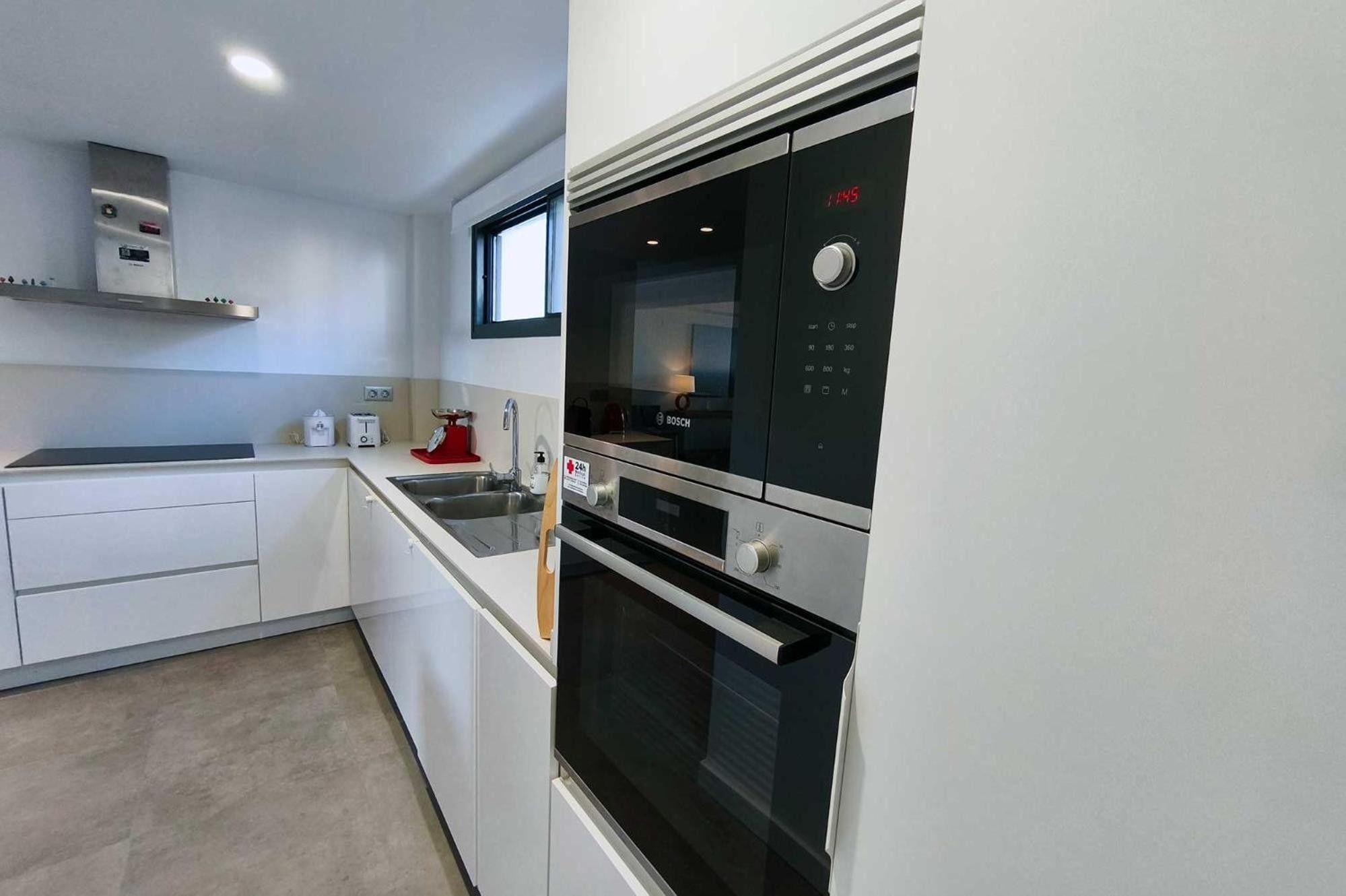 Una cocina moderna con electrodomésticos integrados, un ventanal y un refrigerador Bosch.