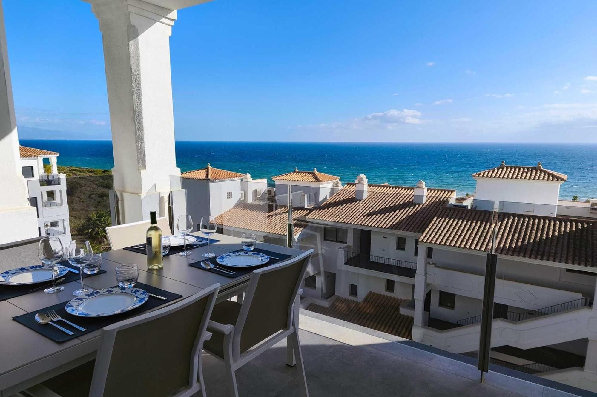 Mesa de comedor para dos con vista al mar y edificios al fondo.