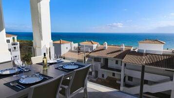 Mesa de comedor para dos con vista al mar y edificios al fondo.