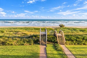A wooden boardwalk leading to a beach with waves in the background. - Beachfront Access | 4BR | Hot Tub | Ocean Views (Galveston)