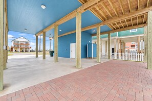 An outdoor covered area with a brick floor, wooden beams, and a blue wall. - Beachfront Access | 4BR | Hot Tub | Ocean Views (Galveston)