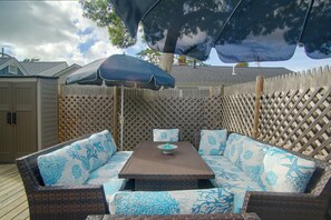An outdoor patio with a wooden table and blue patterned sofa. - Walk to Beach & Eats! Dennis Port Cottage-2 Decks (Dennis Port)
