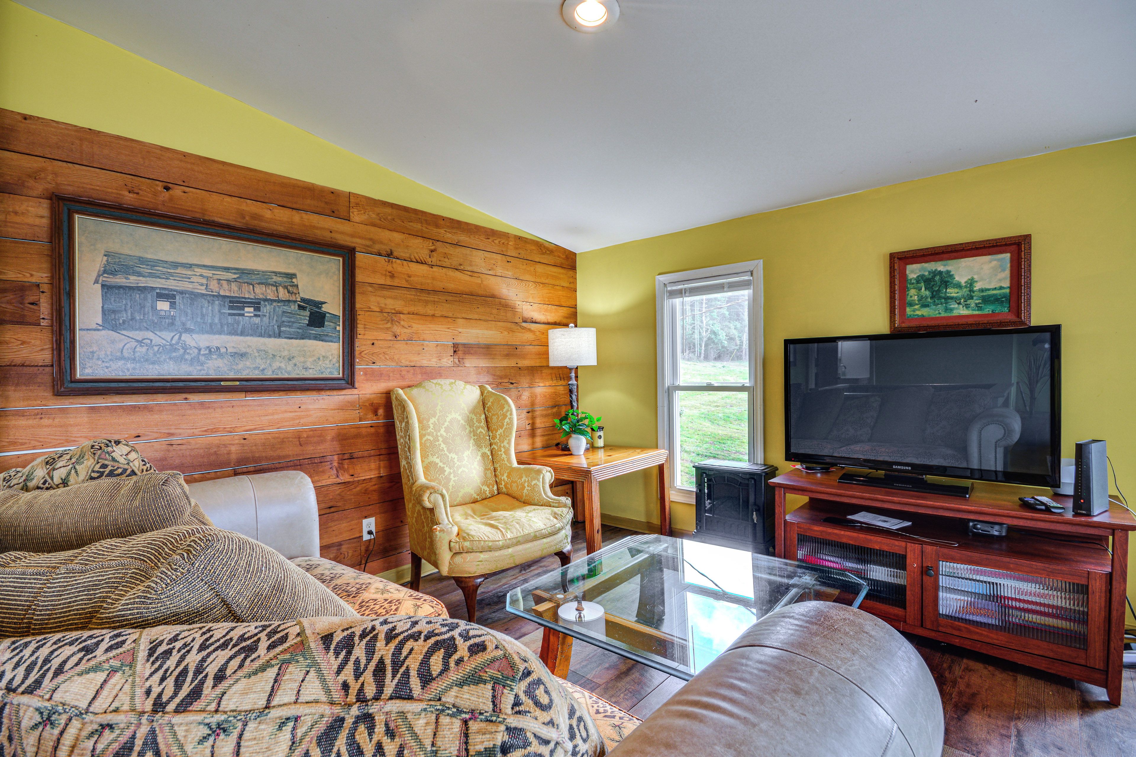 A living room with a wooden wall, a television, a sofa, and a patterned rug.