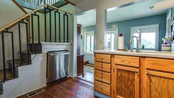 A kitchen with wooden cabinets, a stainless steel refrigerator, and a wooden staircase.