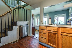 A kitchen with wooden cabinets, a stainless steel refrigerator, and a wooden staircase.