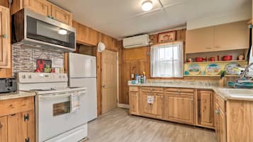 A compact kitchen with wooden cabinets, a microwave, a stove, and a refrigerator.