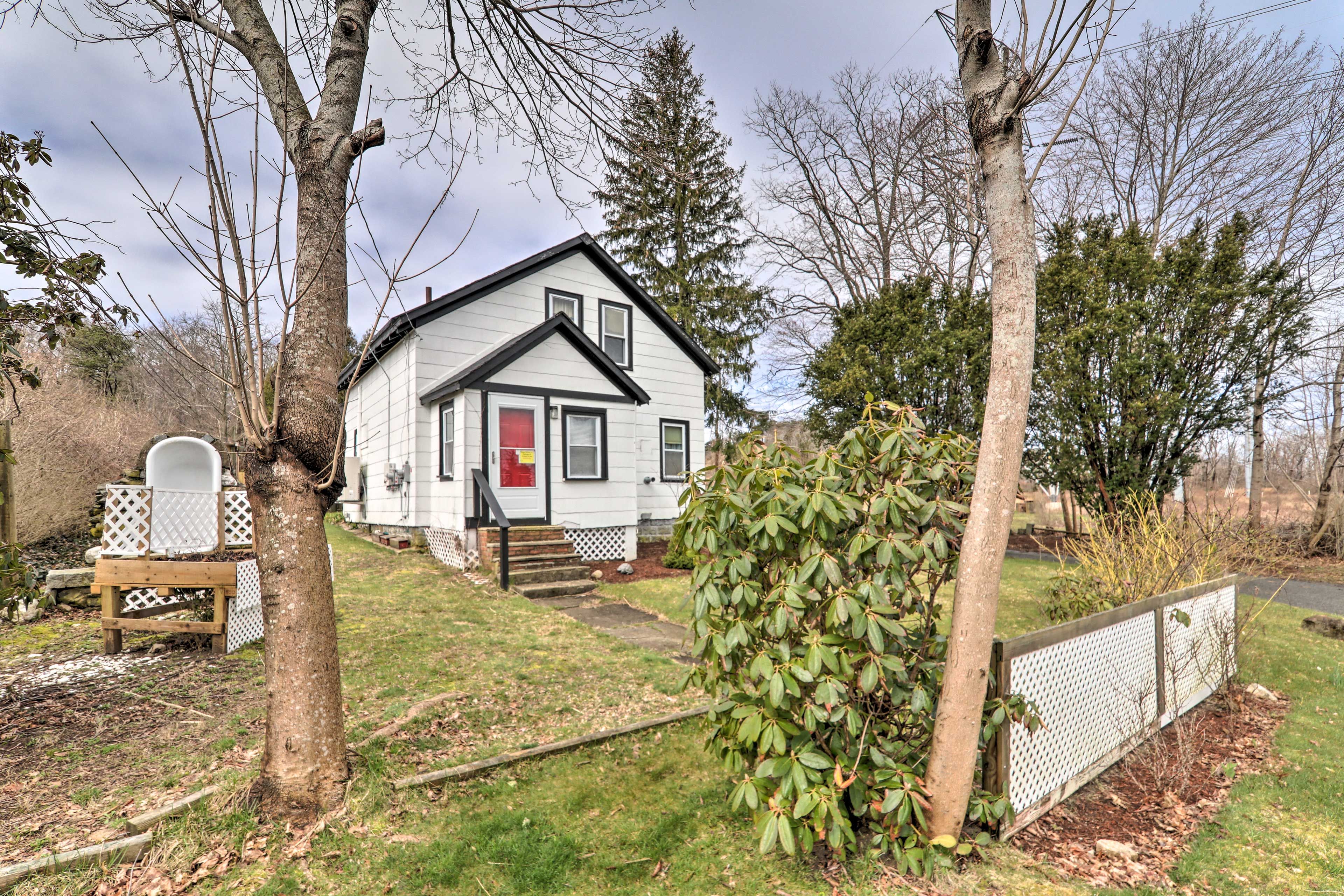 A single-story house with a front door, a small porch, and a fenced yard.