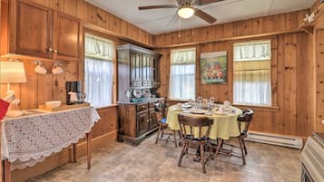 A wooden interior with a dining table set for four, a coffee station, and a ceiling fan.