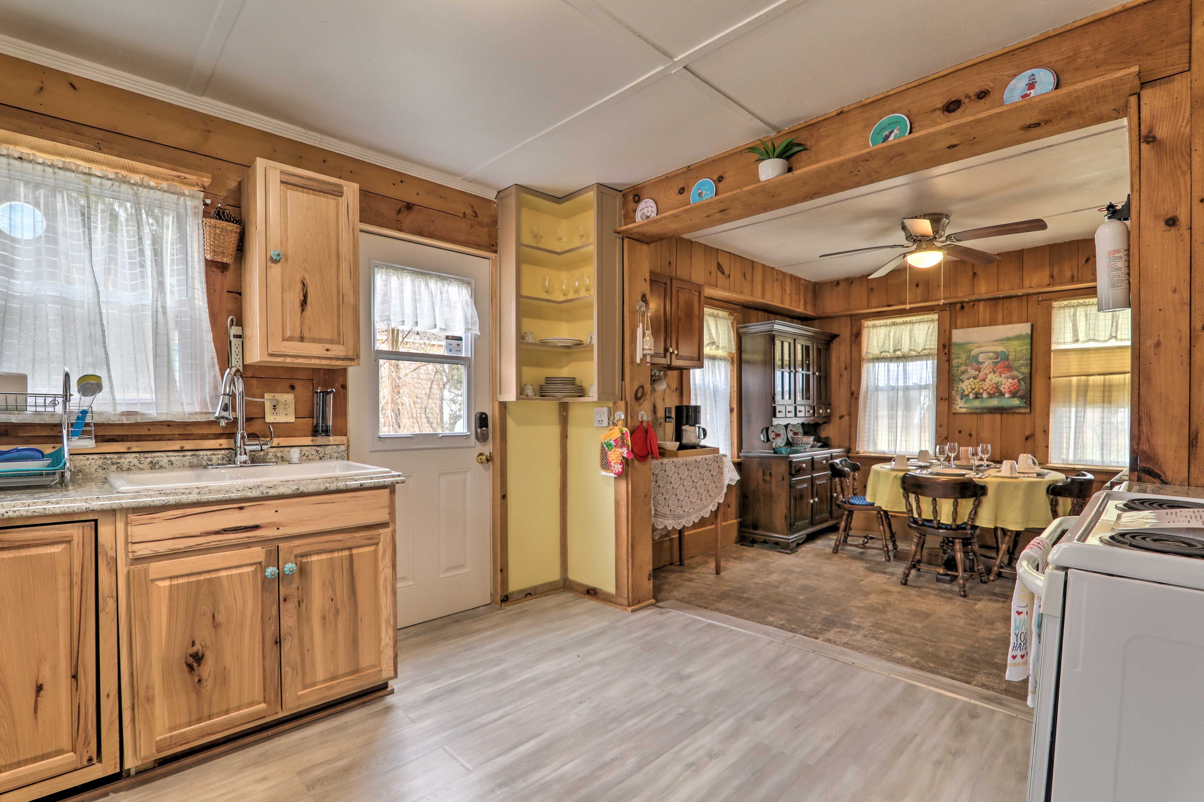 Una cocina con armarios de madera, un fregadero y una zona de comedor con mesa y sillas.