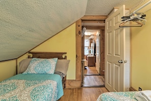 Un dormitorio con techo inclinado, estructura de cama de madera y una puerta que da a un pasillo.
