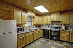 A kitchen with wooden cabinets, a microwave, a stove, and a dishwasher. - 2 Mi to Historic Dtwn! Family Getaway w/ Game Room (Granbury)