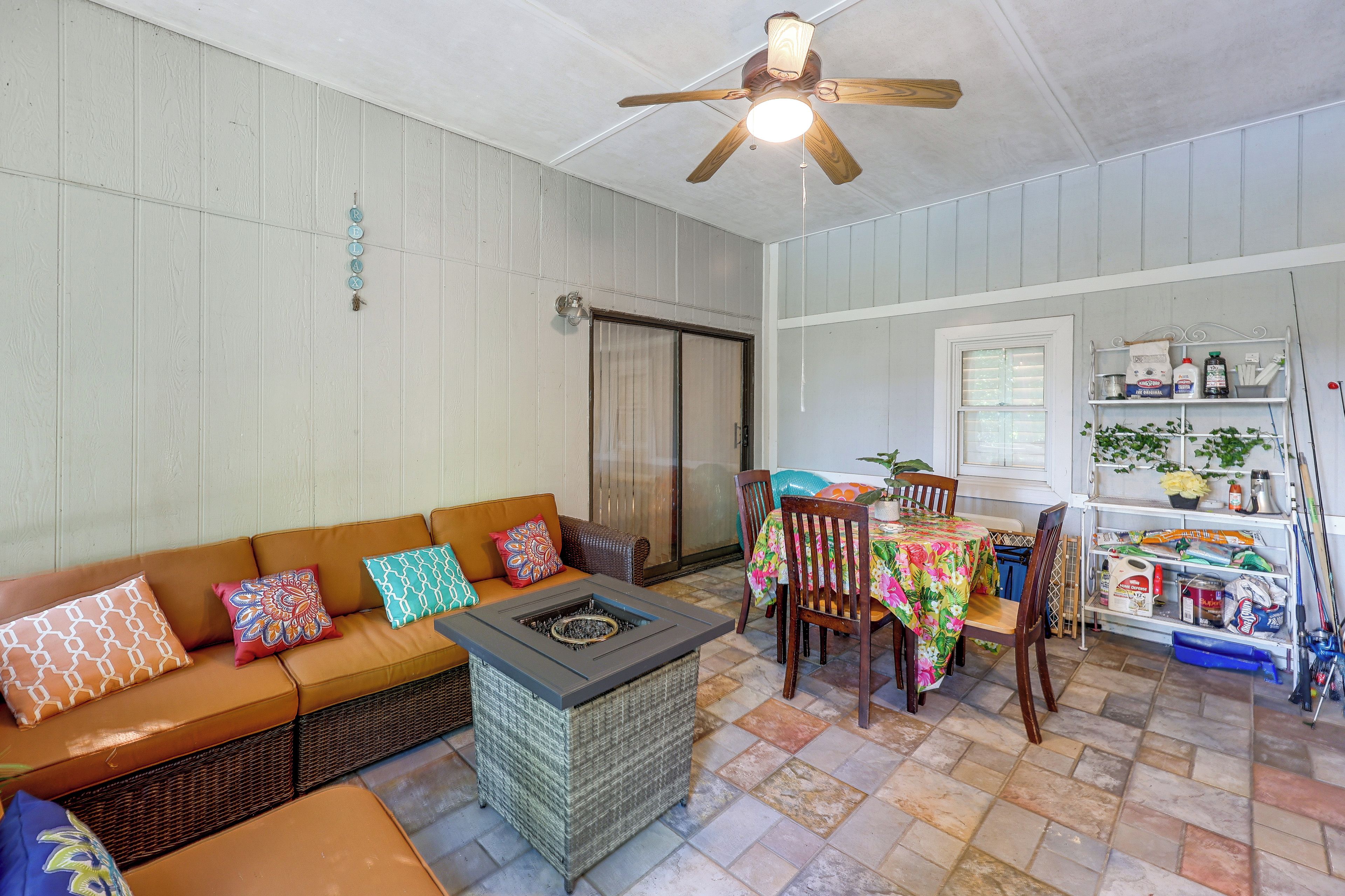 A cozy living area with a sofa, a fire pit, a dining table, and a ceiling fan.