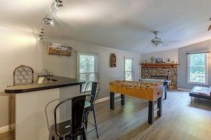 Amplia sala de estar con mesa de fútbol, barra y chimenea.