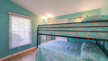 A bedroom with a bunk bed, a window with blinds, and a wall-mounted air conditioning unit.