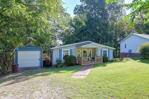 A single-story house with a front porch, a garage, and a small shed.
