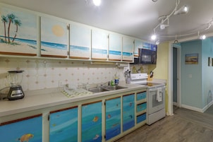 A kitchen with a blender, a microwave, and a sink.