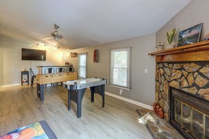 A room with a foosball table, a fireplace, and a television.