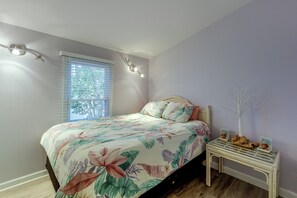 Une chambre à coucher comprenant un lit, une table de chevet, une fenêtre avec des stores et un luminaire fixé au mur.