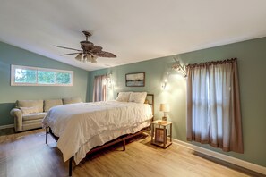 A bedroom with a bed, a nightstand, a lamp, a ceiling fan, and a window with curtains.