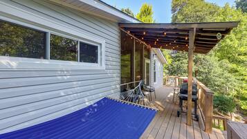 A deck with a pergola, outdoor seating, and a barbecue grill.