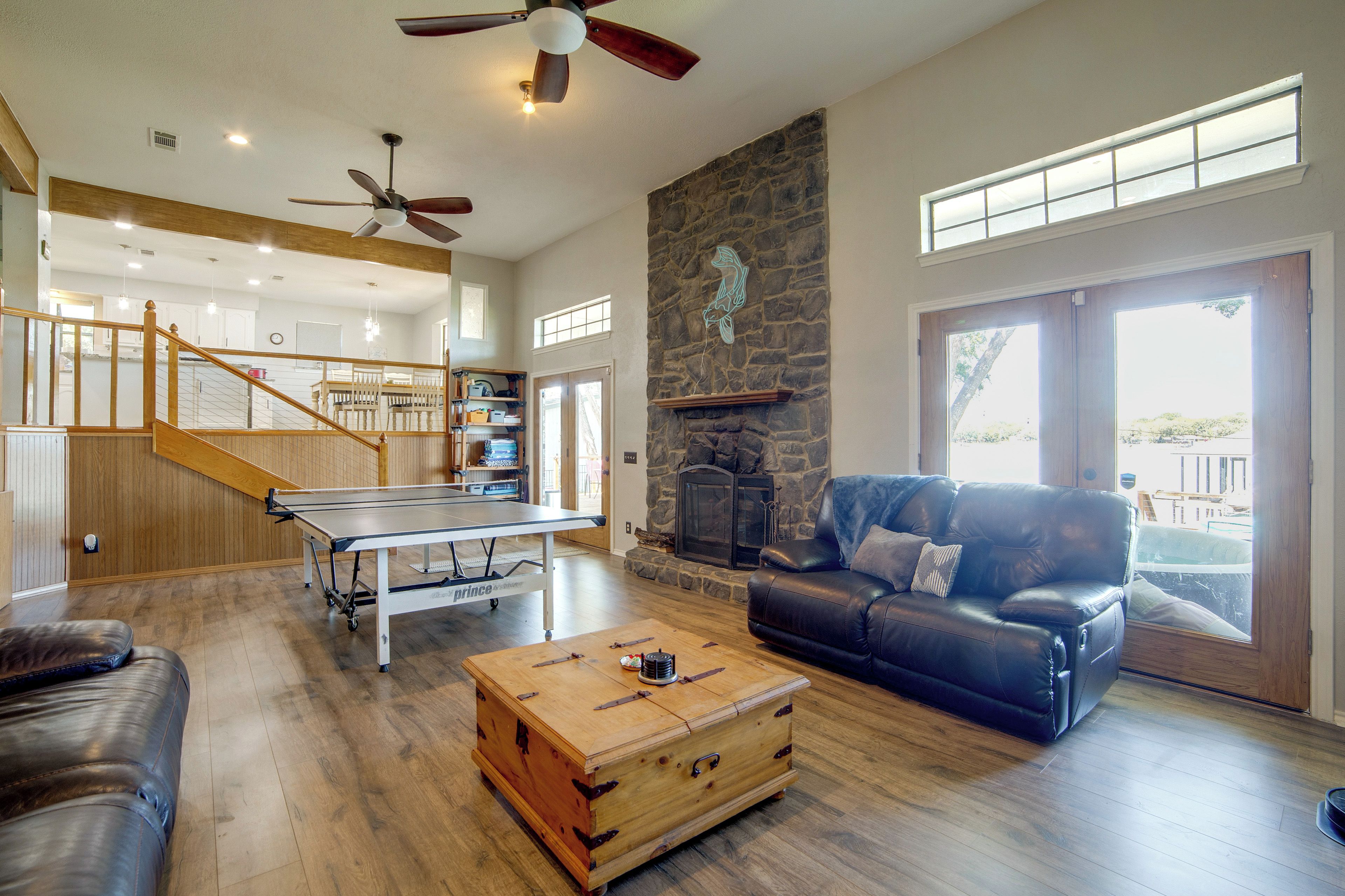 A spacious living area with a ping pong table, leather sofa, and a stone fireplace.