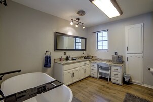Un baño con bañera, lavamanos con espejo, ventana y puerta.