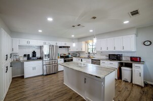 Una cocina moderna con muebles blancos, electrodomésticos de acero inoxidable y una isla central.