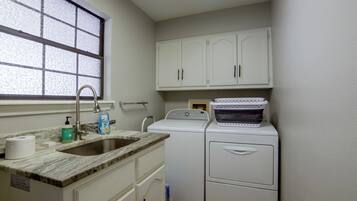 A compact kitchen with a sink, countertop, and a washing machine.