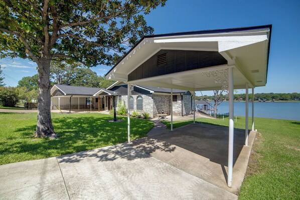 A covered outdoor area with a concrete walkway leading to a building with stone walls and a sloped roof.