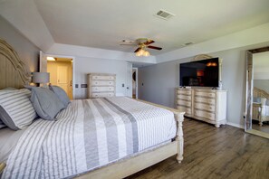 Ein Schlafzimmer mit Bett, Kommode, Spiegel und Deckenventilator.