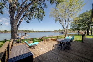 A wooden deck with outdoor furniture, overlooking a lake.