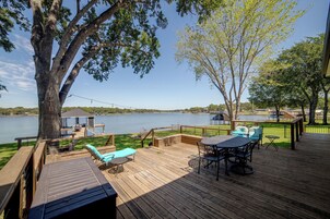 Una terraza de madera con mobiliario exterior, con vista a un lago.