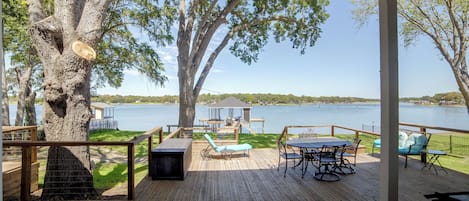 A wooden deck with outdoor furniture overlooking a lake.