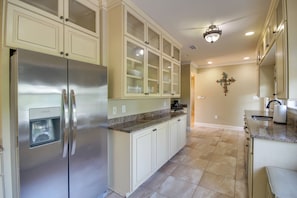 A kitchen with a stainless steel refrigerator, light-colored cabinets, a granite countertop, and a cross-shaped wall decoration. - 1 Block to Beach! Elegant Family Home in Gulfport (Gulfport)