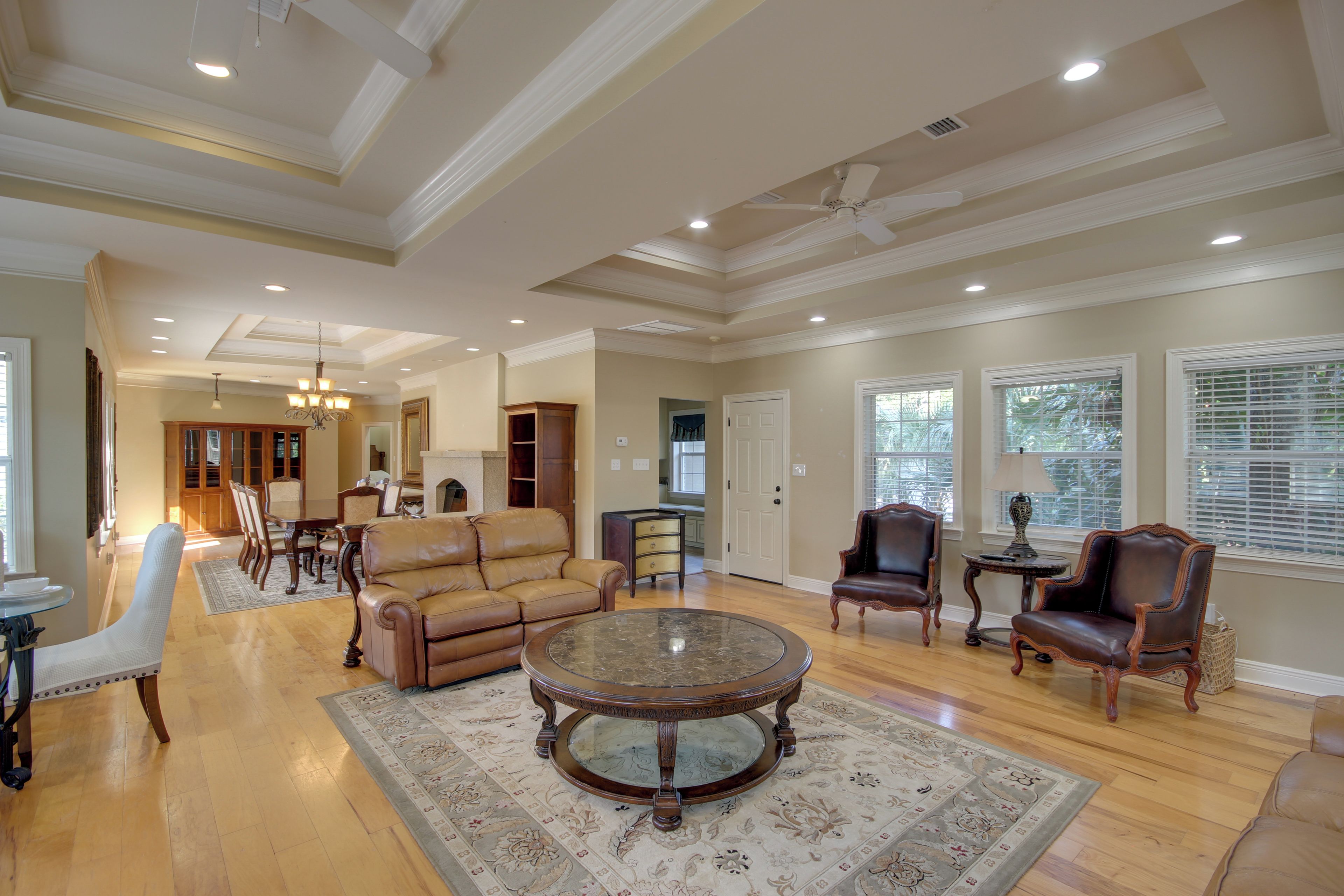 A spacious living room with a leather sofa, a glass coffee table, and a dining area with wooden furniture.