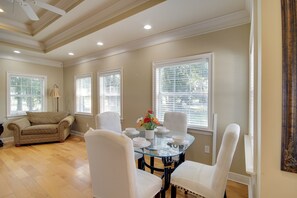 A dining area with a round glass table, white chairs, and a beige sofa. - 1 Block to Beach! Elegant Family Home in Gulfport (Gulfport)