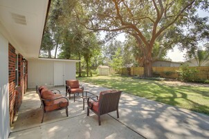 A patio with outdoor furniture, a covered area, and a yard with trees and a fence.