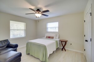A bedroom with a bed, a ceiling fan, a small round table, and a leather couch.