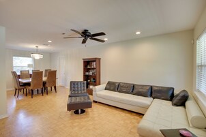 A living room with a sofa, ottoman, and a dining area with chairs and a table.