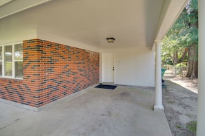 A covered porch with a brick wall, a white door, and a concrete floor. - < 2 Mi to Beach! Home w/ Fenced Yard in Gulfport (Gulfport)