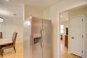 A kitchen with a stainless steel refrigerator, wooden dining table, and chairs.