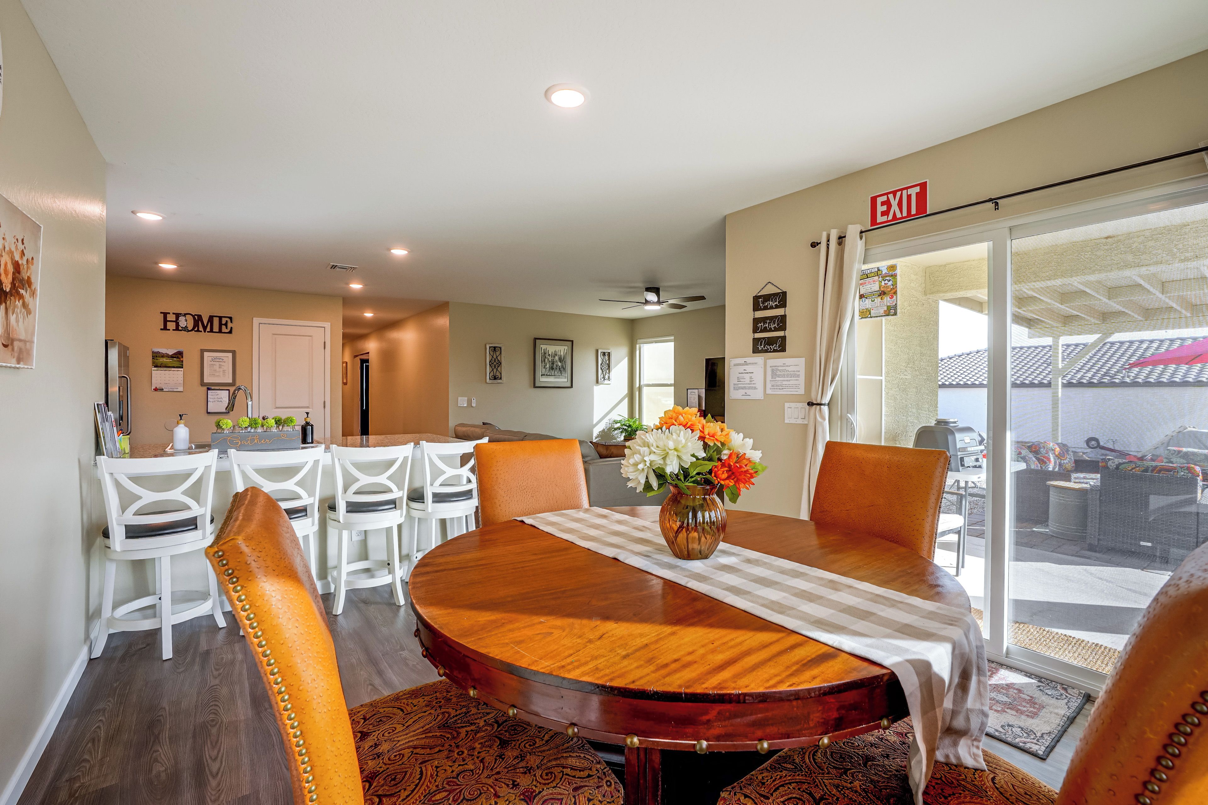 A dining area with a round wooden table, white chairs, and a vase of flowers.
