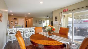A dining area with a round wooden table, white chairs, and a vase of flowers.