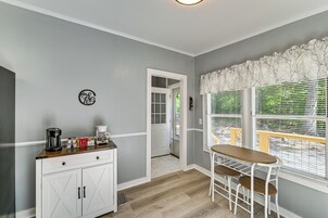 Una cocina con cafetera, armarios y una ventana con persianas.
