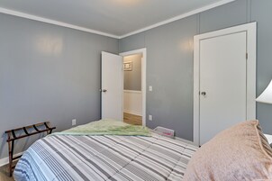 Un dormitorio con cama, una silla, un armario y una puerta que da a un vestidor.