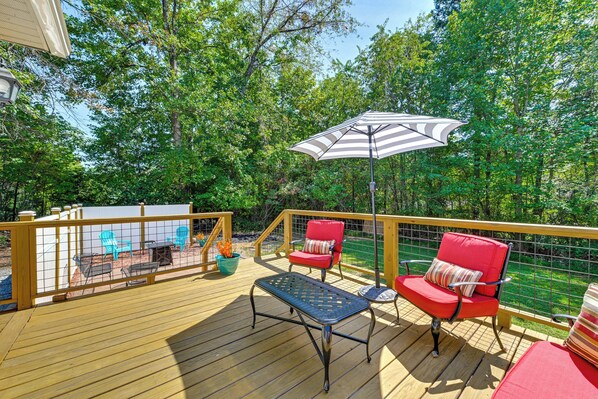 A wooden deck with outdoor furniture, including chairs and a table, and a large umbrella providing shade.