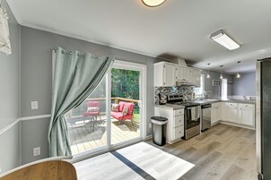 Una cocina moderna con puerta corredera de vidrio que da a una terraza exterior, estufa empotrada y muebles de cocina blancos.
